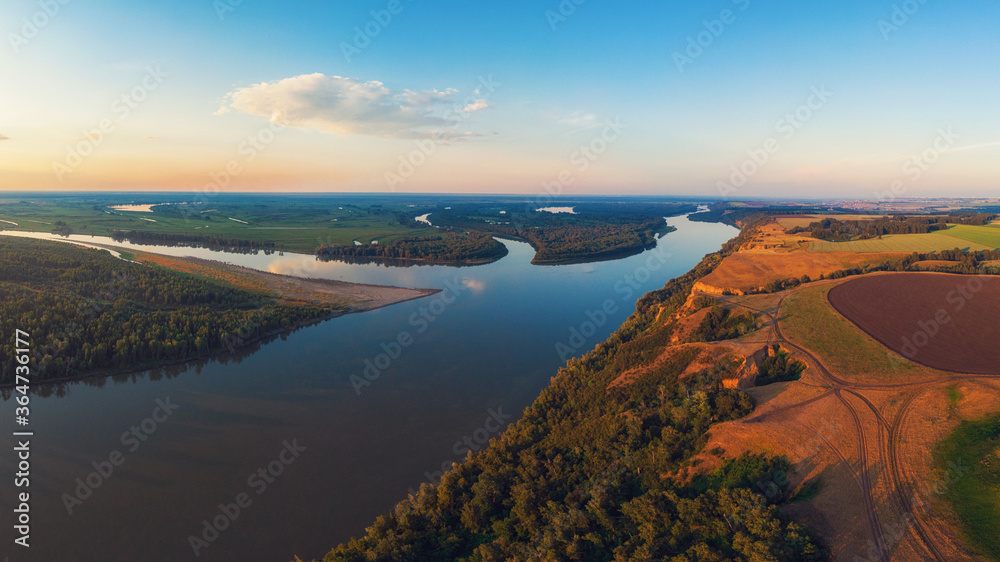 Aerial drone view of river landscape in sunny summer evening. Top view of siberian Ob river from hig