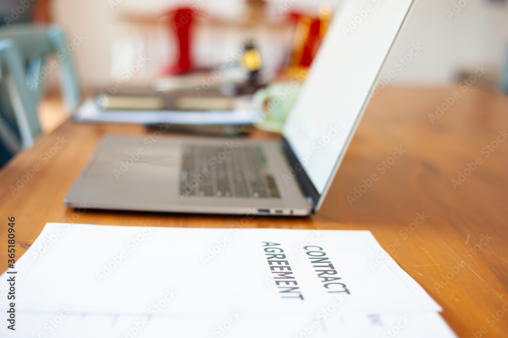 Contract documents, agreements and laptops on the attorneys desk in the office.