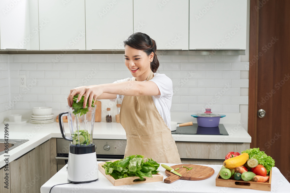 家庭主妇用新鲜水果和绿色蔬菜烹饪健康排毒奶昔