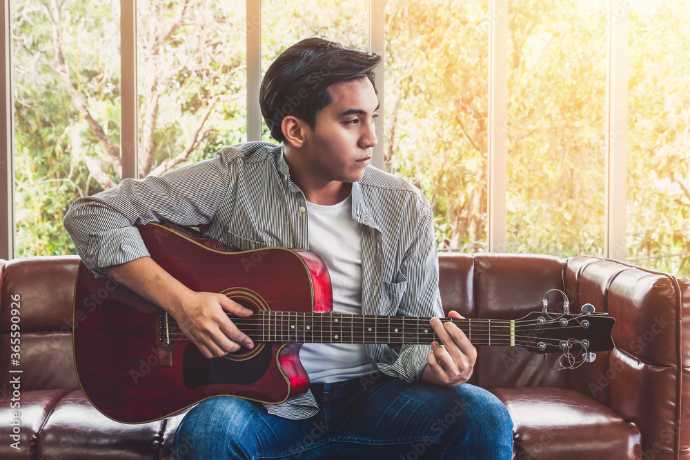 Young guitar player holding his guitar at home. Music and song concept.