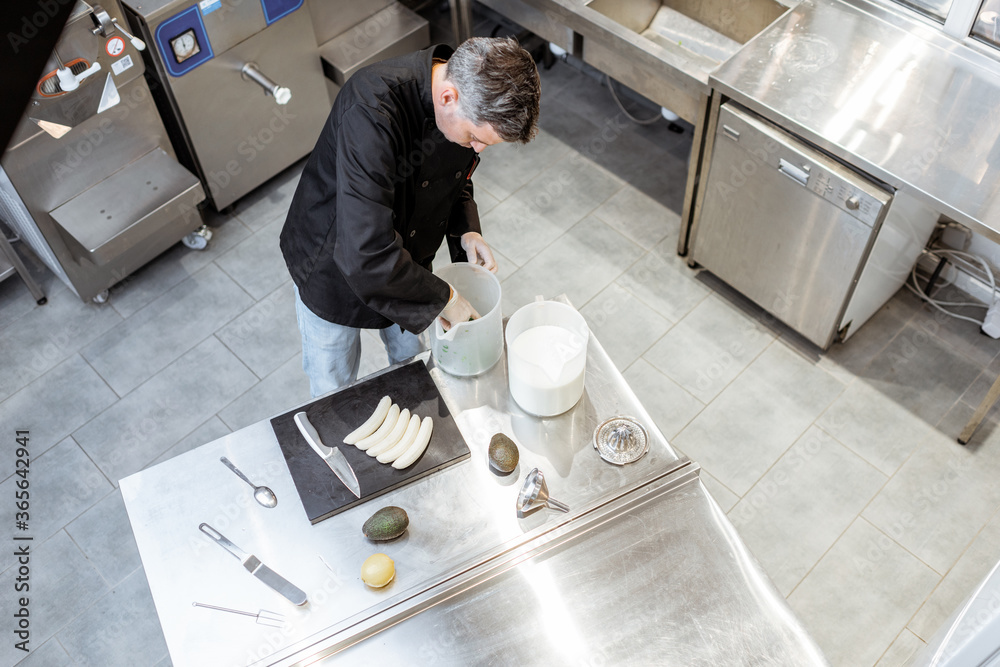 Portrait of a professional chef in black uniform cooking on the kitchen at the small ice cream manuf