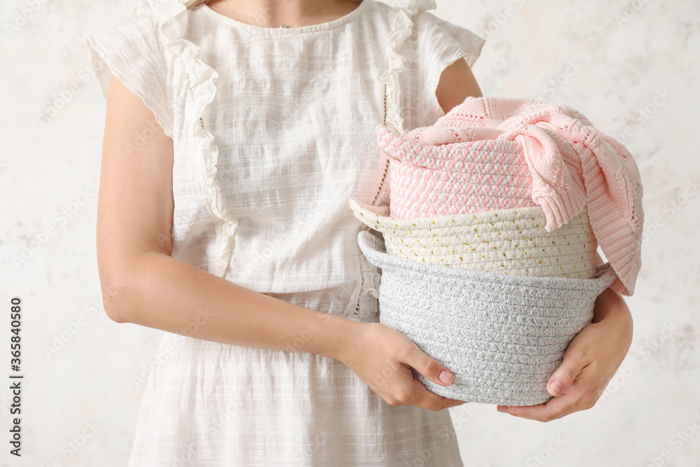 Woman holding wicker baskets with plaid on light background