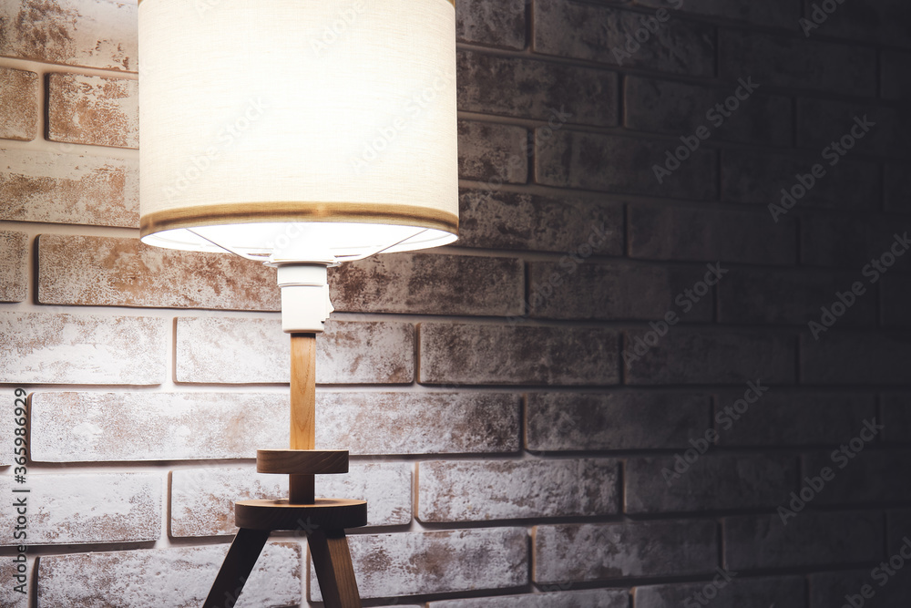 Glowing lamp near brick wall in evening