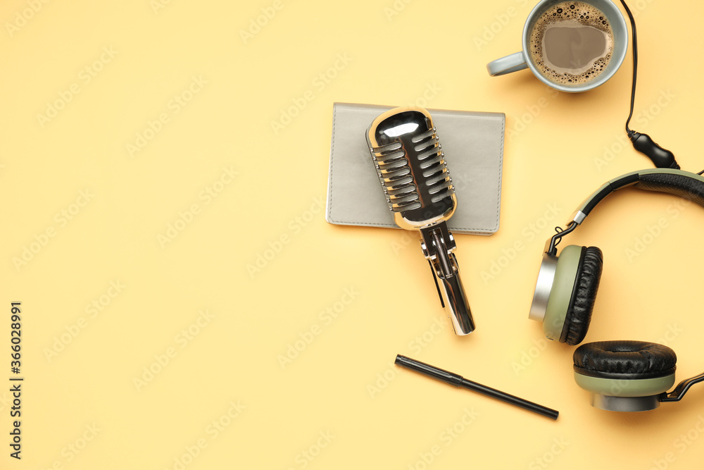 Headphones with microphone, notebook and cup of coffee on color background