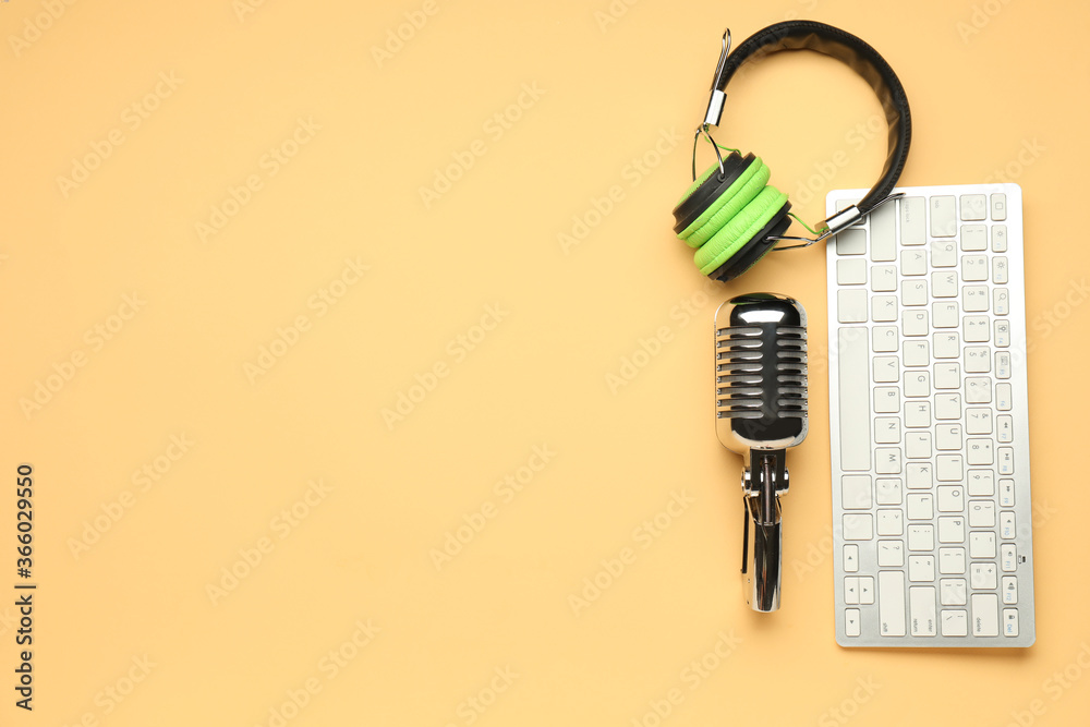 Headphones with microphone and computer keyboard on color background