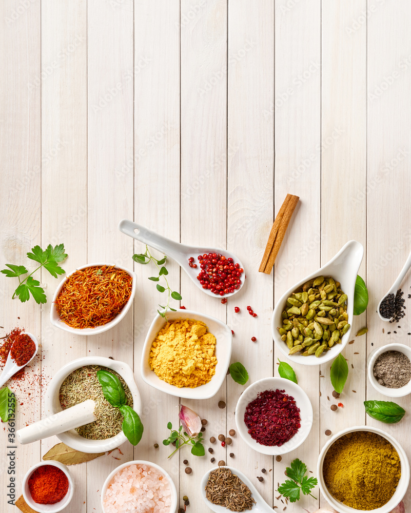 Different indian spices in a bowls and herbs on white wooden background. Top view of indian spices w