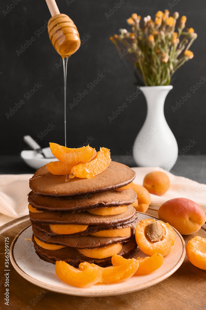 Pouring of honey onto delicious chocolate pancakes