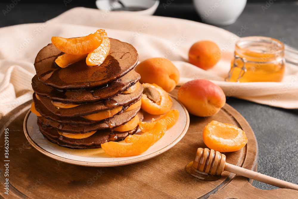 Plate with delicious chocolate pancakes and apricot on table