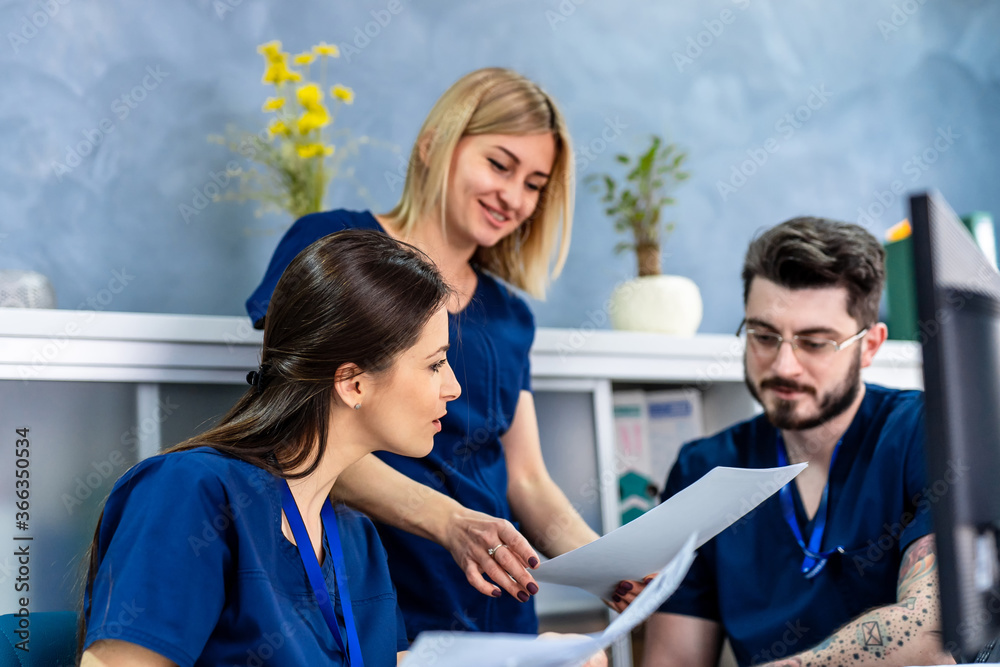 Doctors are working on medical expertise while sitting at desk in front of computer.