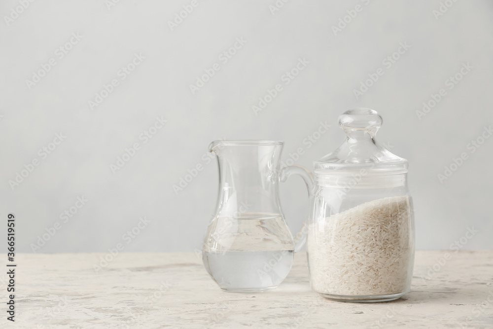 Jar with rice and jug of water on table