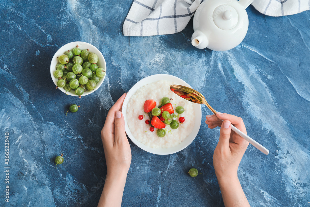 Woman eating tasty boiled rice with berries