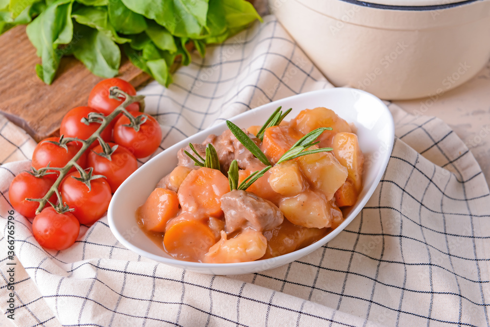 Bowl with tasty beef stew on table