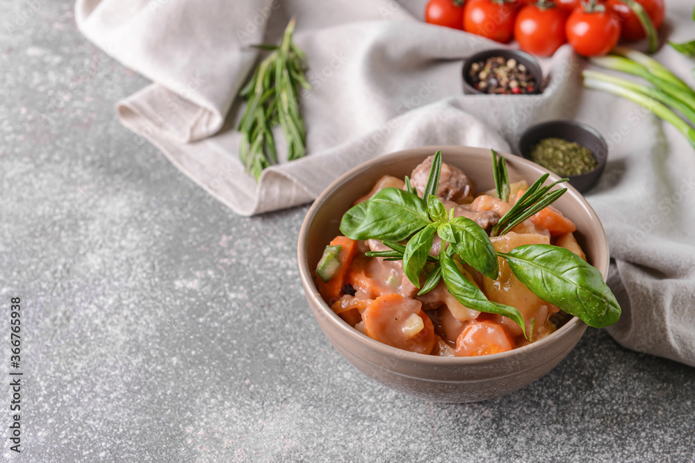 Bowl with tasty beef stew on grey background