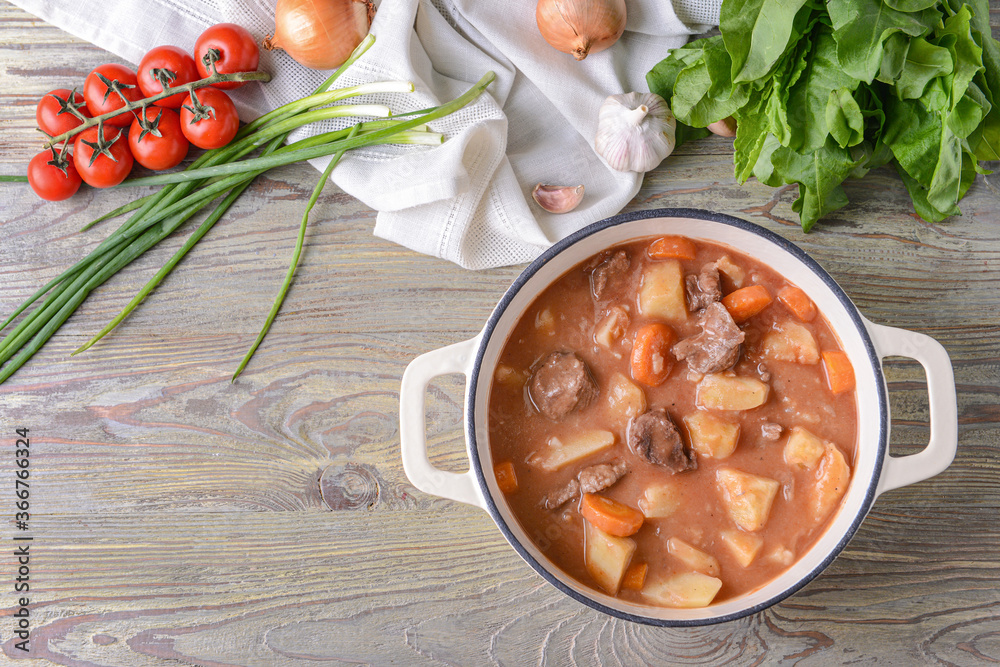 Pot with tasty beef stew on table