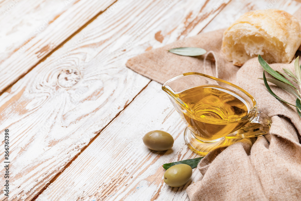 Gravy boat of tasty olive oil and bread on wooden background