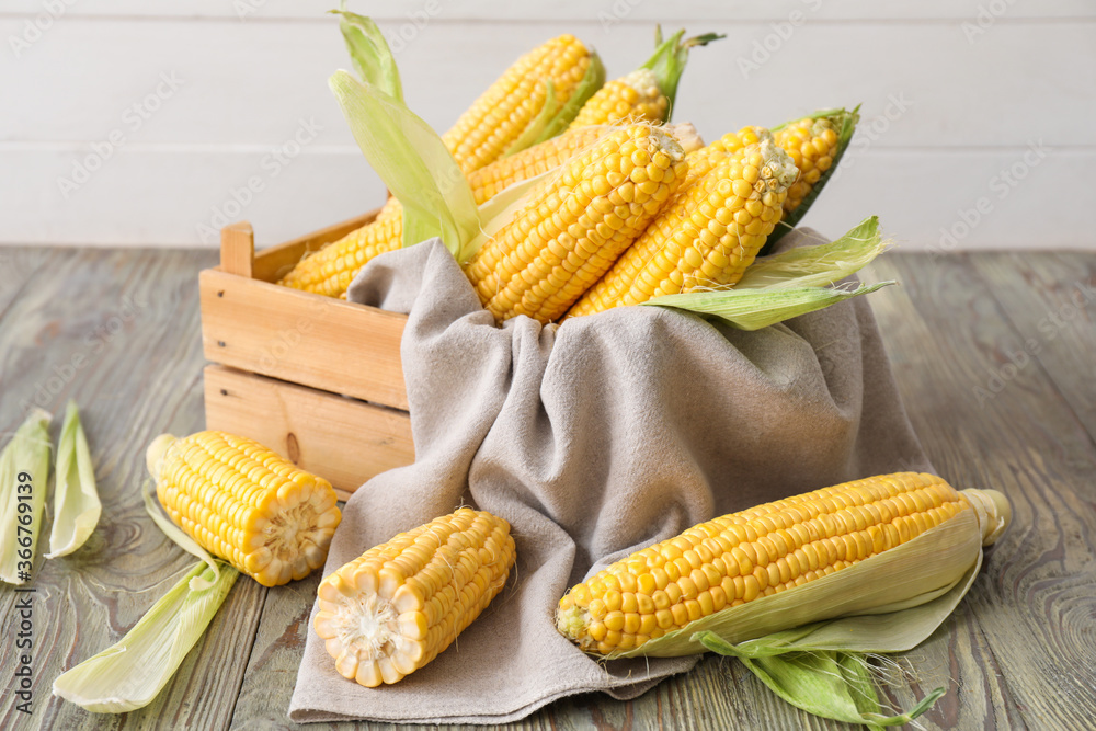 Box with fresh corn cobs on table