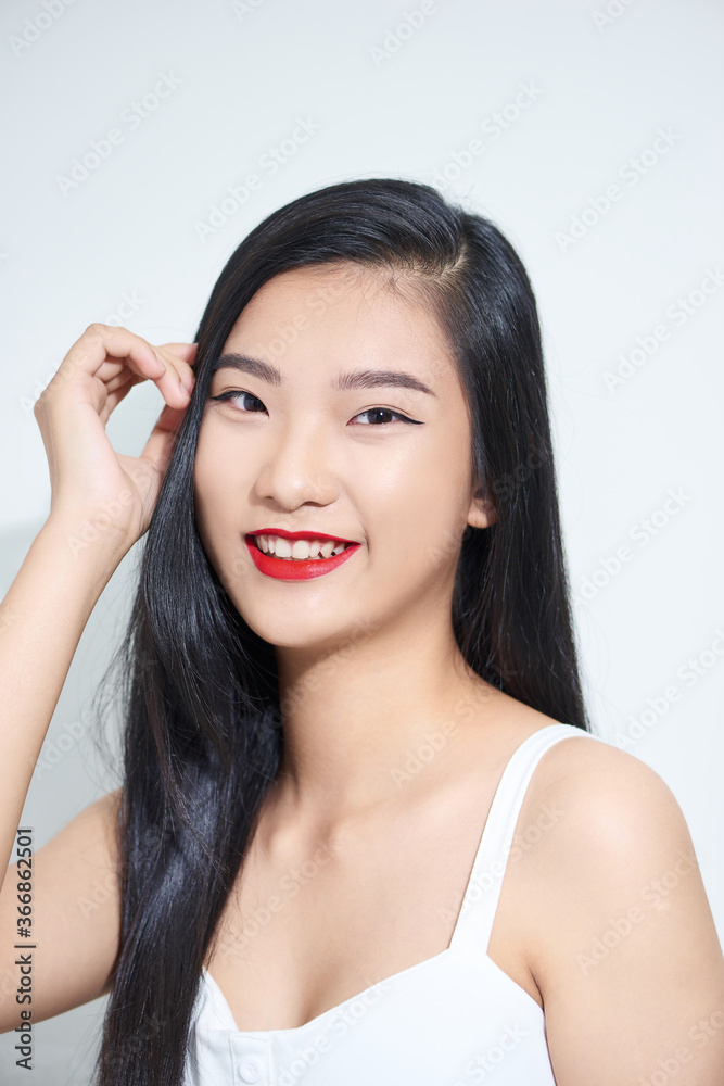 lifestyle and people concept - Beautiful happy asian girl touches her hair. Casual clothes. White ba