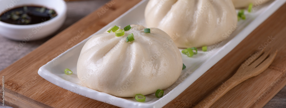 Delicious baozi, Chinese steamed meat bun is ready to eat on serving plate and steamer, close up, co