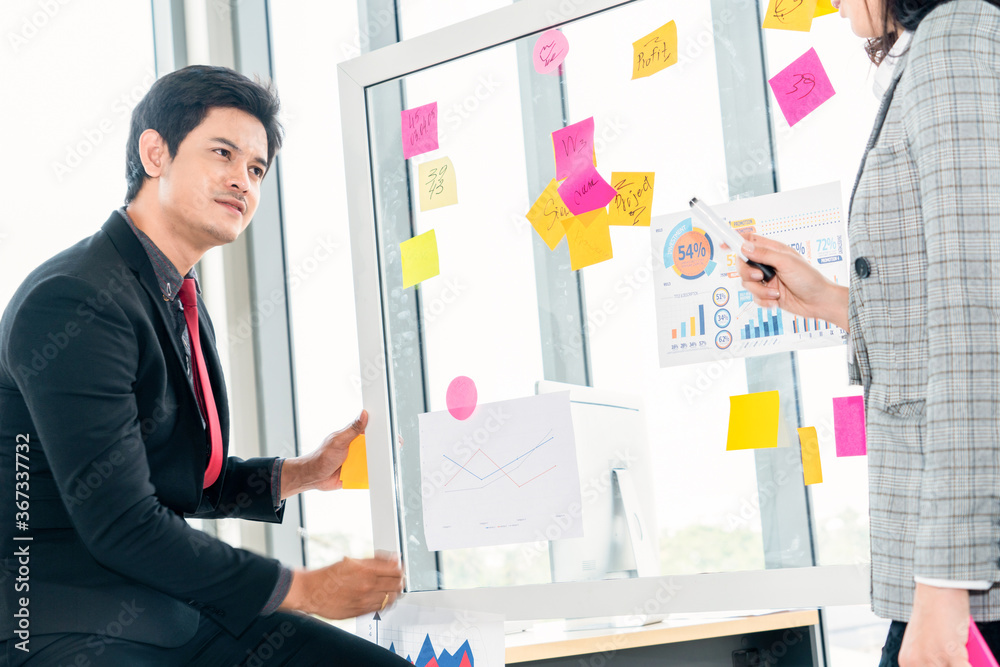 Business people work on project planning board in office and having conversation with coworker frien