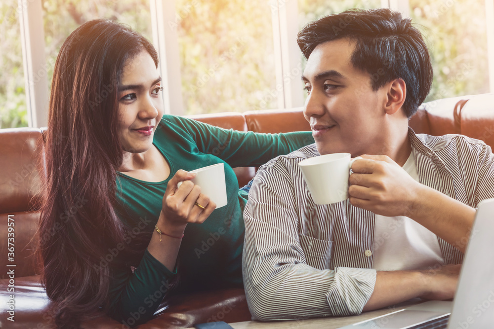 Happy Asian couple drink coffee at home. Love relationship and lifestyle concept.