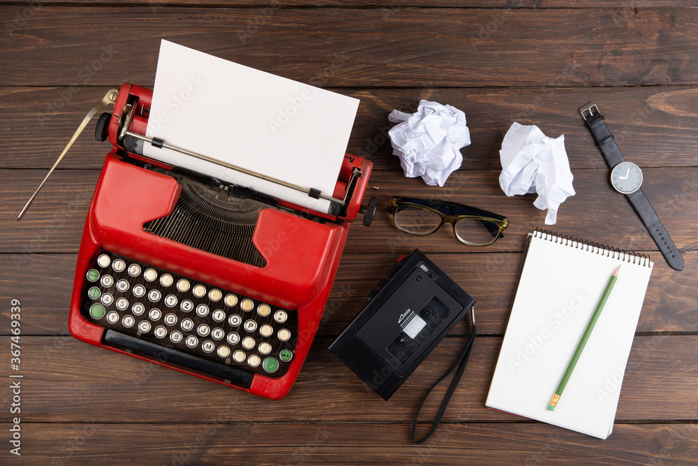 Writer or journalist workplace - vintage red typewriter, cassette recorder and notepad on the wooden