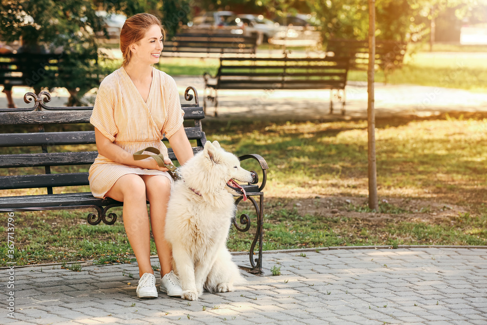 公园里年轻女子带着可爱的萨摩耶犬