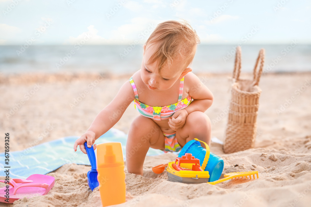 Cute baby girl with sunscreen cream on beach