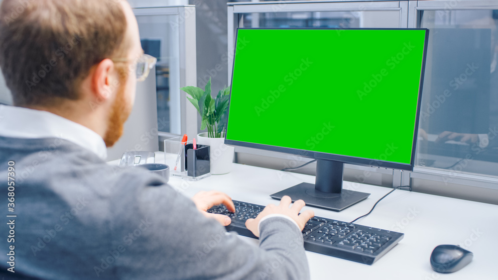 Over the Shoulder Shot of Motivated Office Worker Using Green Mock-up Screen Desktop Computer in the