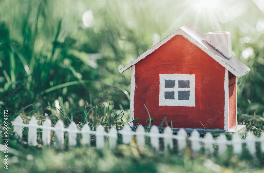 red wooden house model on the grass