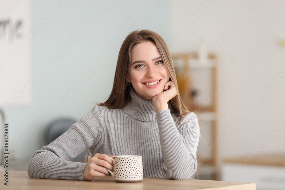 美丽的年轻女人在家喝茶