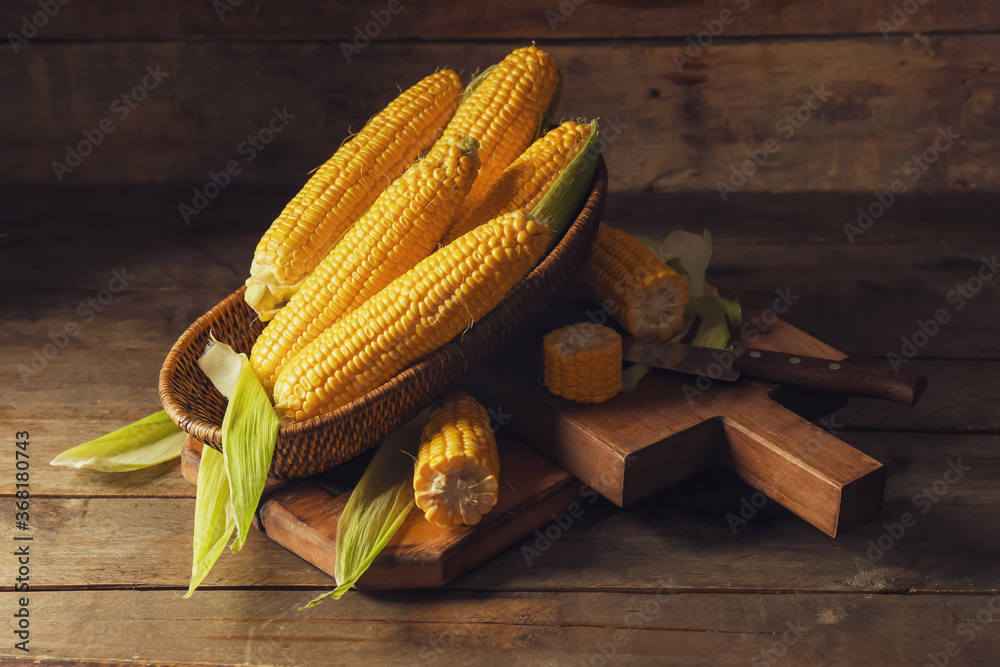 Basket with fresh corn cobs on table