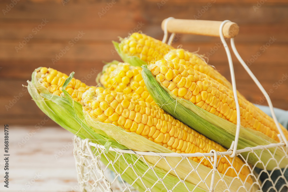 Basket with fresh corn cobs on table, closeup