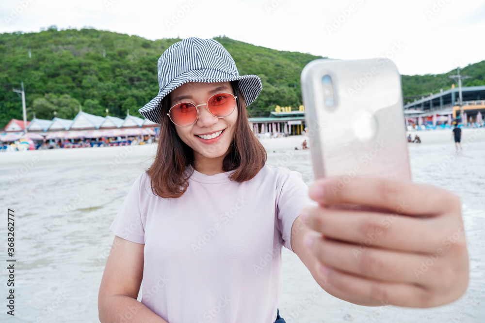 女性游客晚上在海边用手机自拍。