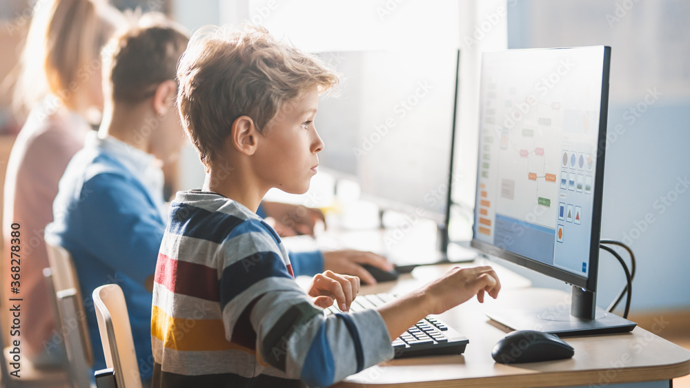 Elementary School Science Classroom: Smart Little Schoolchildren Sitting in Row and Work on Personal