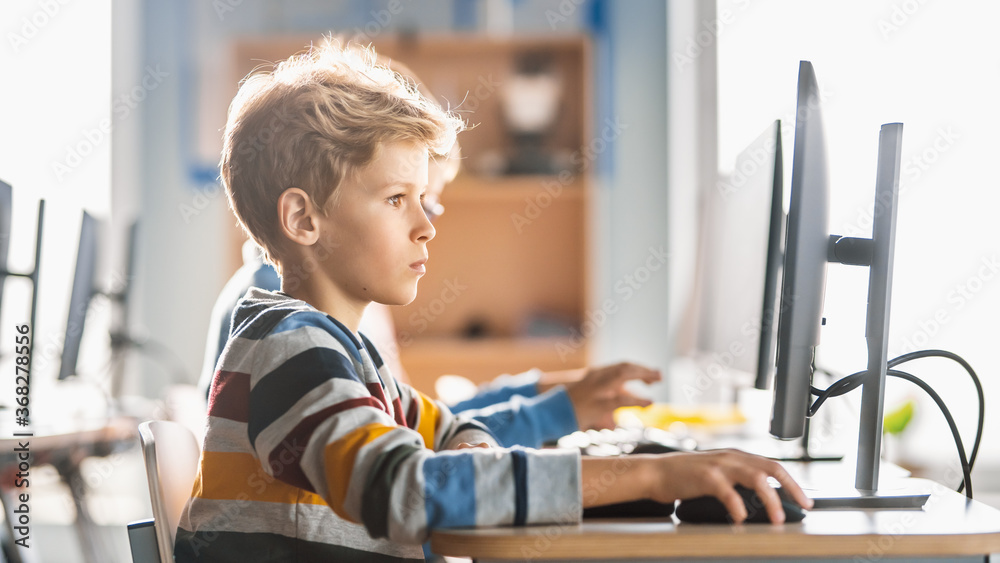 Elementary School Computer Science Classroom: Cute Little Boy Uses Personal Computer, Learning Progr