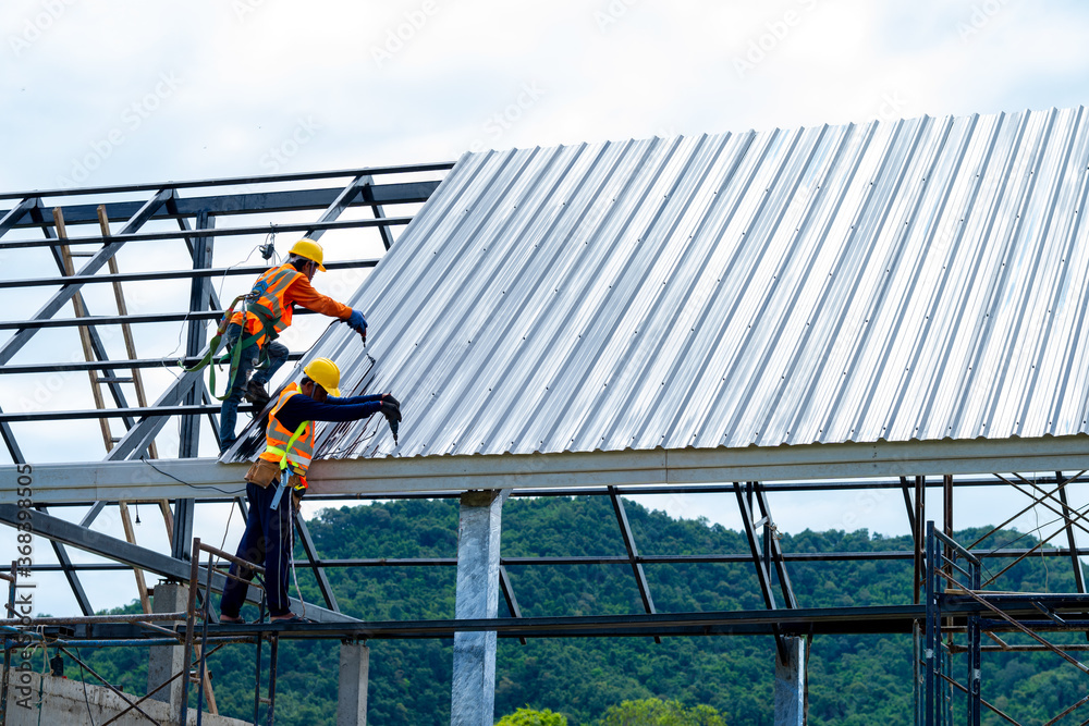 穿着防护服、戴着手套的屋顶工人安装新屋顶，住宅建筑概念