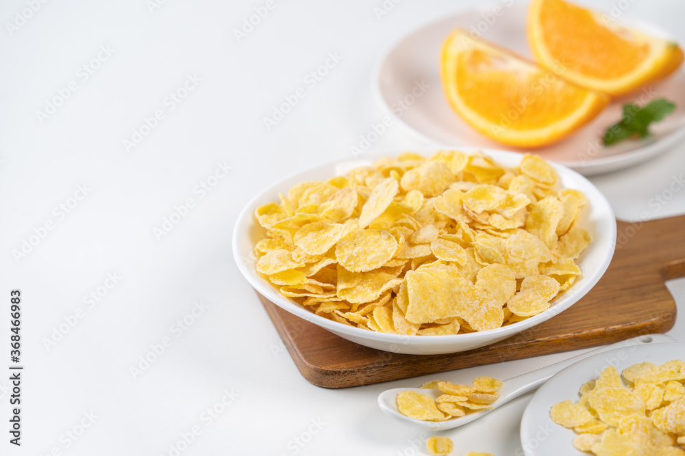 Corn flakes bowl sweeties with milk and orange on white background, close up, fresh and healthy brea