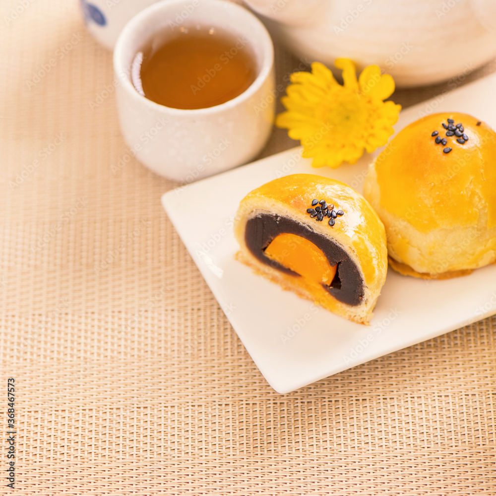 Tasty baked egg yolk pastry moon cake for Mid-Autumn Festival on bright wooden table background. Chi