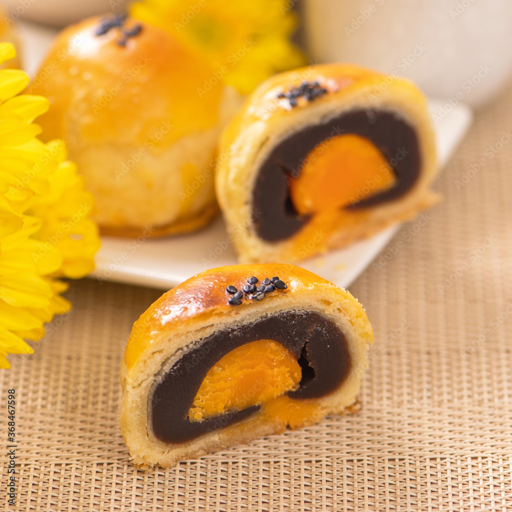 Tasty baked egg yolk pastry moon cake for Mid-Autumn Festival on bright wooden table background. Chi