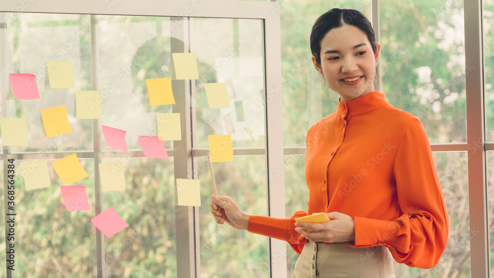 Business people work on project planning board in office and having conversation with coworker frien