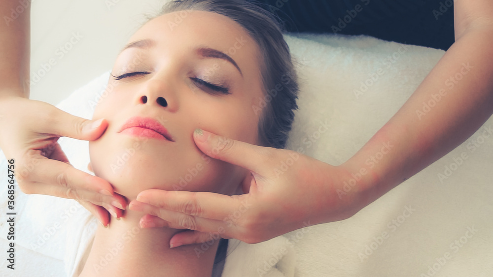 Relaxed woman lying on spa bed for facial and head massage spa treatment by massage therapist in a l