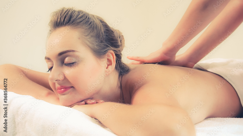 Relaxed woman getting back massage in luxury spa with professional massage therapist. Wellness, heal