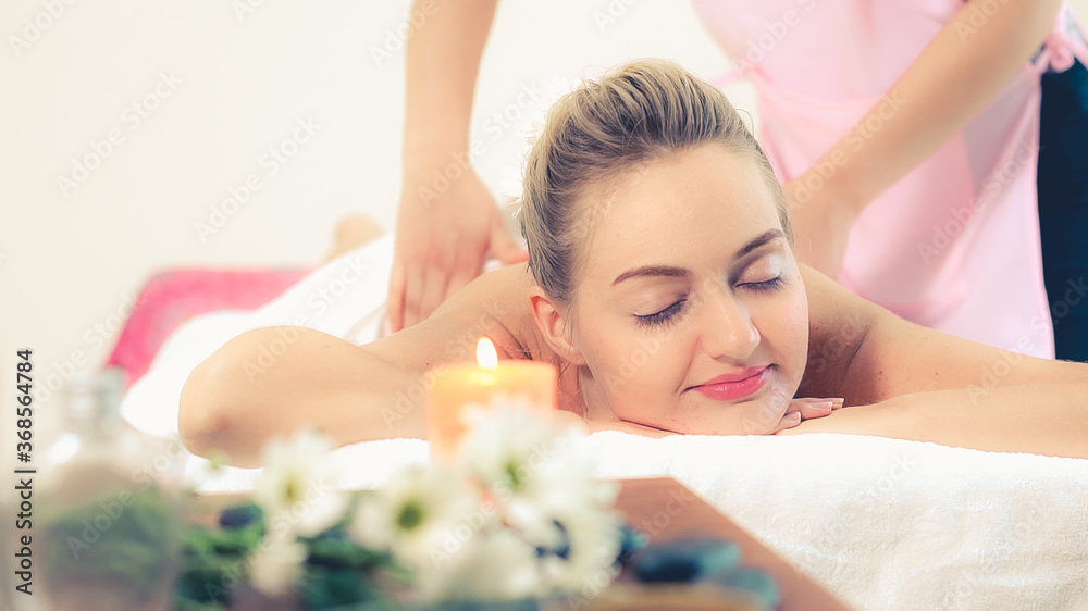 Relaxed woman getting back massage in luxury spa with professional massage therapist. Wellness, heal