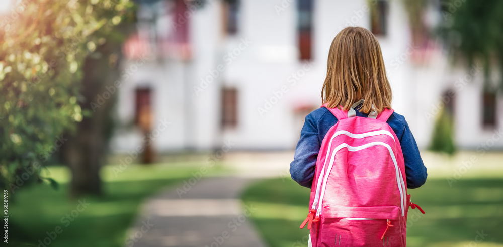 学校大楼前背着帆布背包的女孩