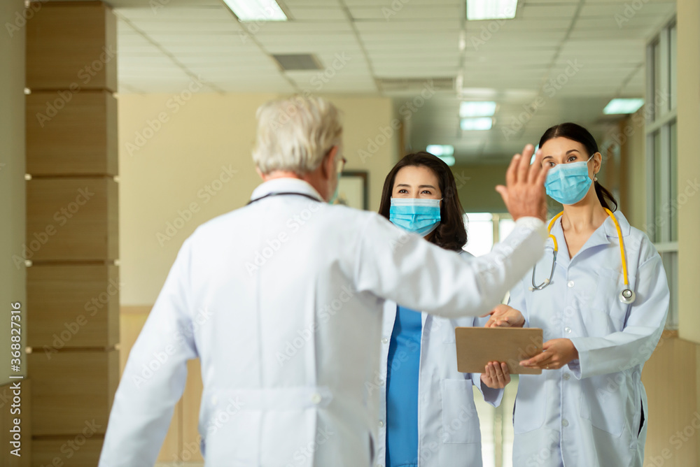 Professional  doctors  wearing mask consult while walking  at hospital