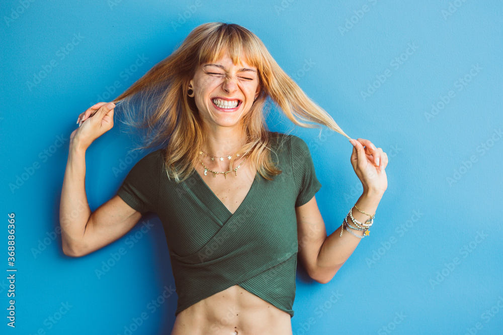 Isolated happy funny woman having fun over a blue background. Portrait of a positive joyful girl