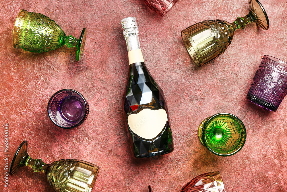 Bottle of champagne and glasses on color background