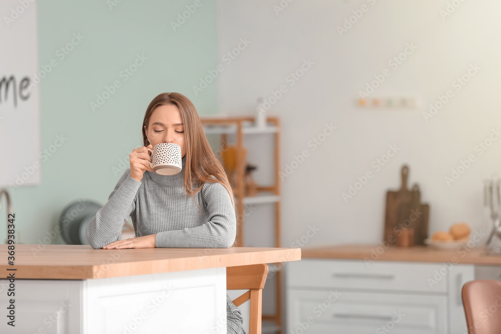 美丽的年轻女人在家喝茶