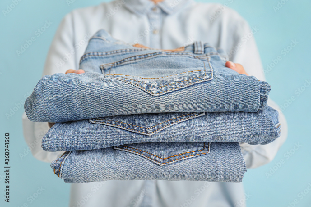 Woman with stylish jeans pants on color background, closeup