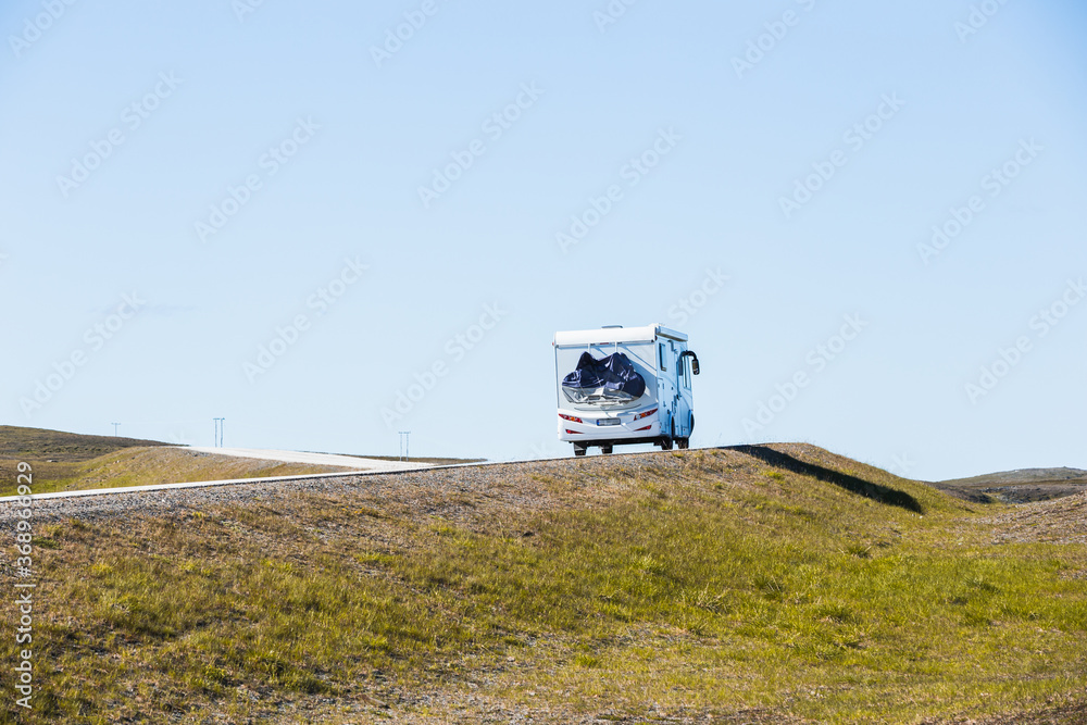 一辆旅行大篷车，又称露营车，行驶在前往挪威北部北开普省的风景优美的道路上